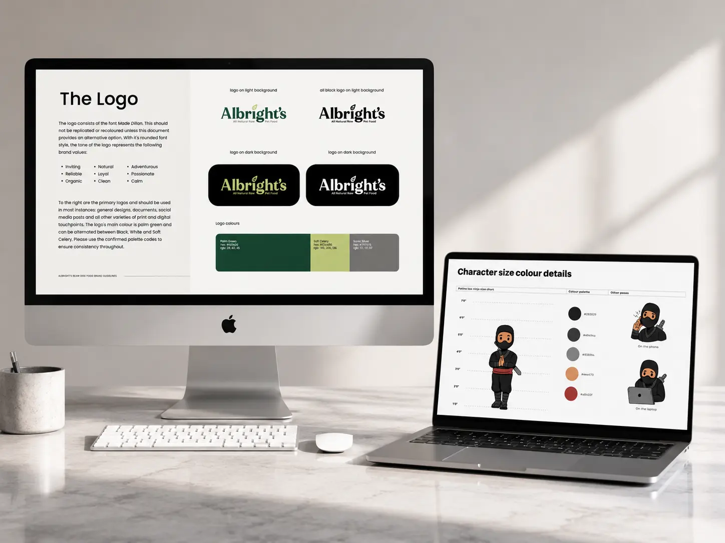 iMac and laptop on a desk displaying two brand style guides: Albright's pet food logo variations and color palette on the desktop, and a ninja character size and color chart on the laptop